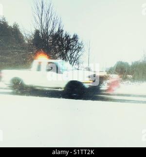 Camionnette avec pelle chasse-neige attaché conduire sur route couverte de neige pendant une chute de neige dans le sud de l'Ontario, Canada Banque D'Images