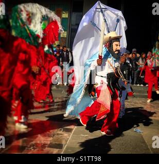 Un homme habillé en Saint Jacques Apôtre équitation son cheval et tenant son épée entouré par des danses de diables au cours de notre pèlerinage de Notre-Dame de Guadalupe à Mexico Banque D'Images