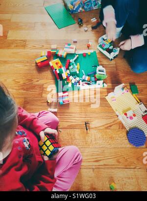 À partir de la vue ci-dessus de deux jeunes enfants jouant avec des Rubik's cube et les blocs de LEGO sur un sol en bois Banque D'Images