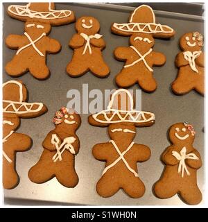 Une plaque est rempli d'inspiration mexicaine gingerbread cookies avec les hommes en pain d'épice sombreros et femmes occupant des zantedeschias. Banque D'Images