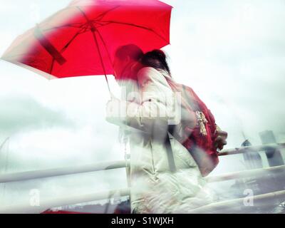 Femme tenant un parapluie une marche sous la pluie. Banque D'Images