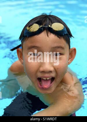 Garçon chinois avec des lunettes de natation fait drôle de visage Banque D'Images