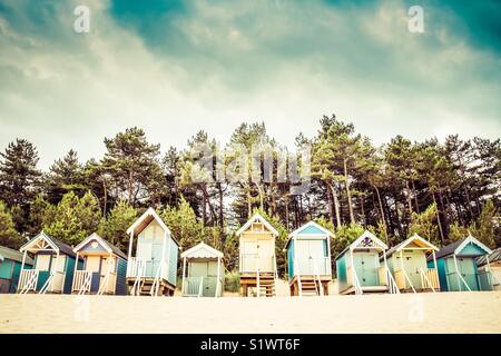 Rangées de cabines de plage exotique sous un ciel dramatique sur la plage de sable de Wells Next The Sea in Norfolk, UK Banque D'Images