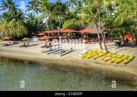 Exotique resort sur l'île de Bora-Bora Polynésie française dans le Pacifique Sud. Des kayaks et des rigueurs aligner la plage attendent les clients à aller dans l'eau dans la lagune. Banque D'Images