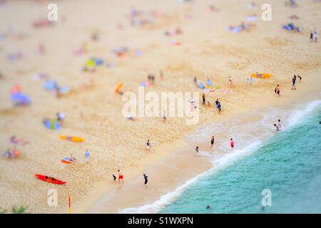 Une vue aérienne d'une longue plage de sable pendant les vacances d'été montrant les familles et amis jouant, le surf et la natation dans l'océan vert émeraude, d'en haut. Banque D'Images