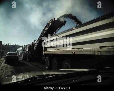 L'asphalte est dépouillé d'une route en construction et chargé dans un camion. Banque D'Images