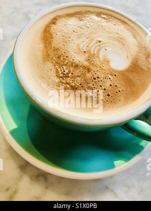 Café blanc plat servi dans un bol vert Banque D'Images