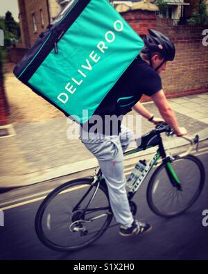 Deliveroo courier cycle portant un repas à emporter à un client après avoir pris le relais dans un restaurant. UK Banque D'Images