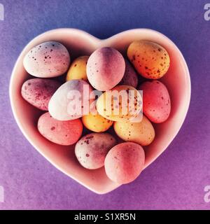 Les oeufs de Pâques en chocolat dans un plat en forme de coeur en céramique Banque D'Images