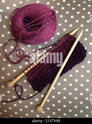 Commencer à tricoter un foulard en laine de couleur framboise. Banque D'Images