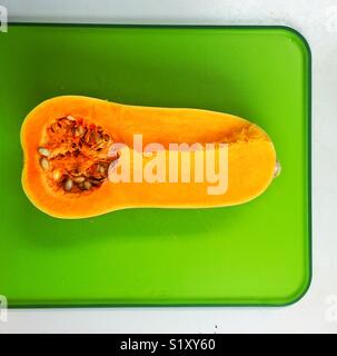 Courge Butternut coupée en deux sur une planche à découper verte Banque D'Images