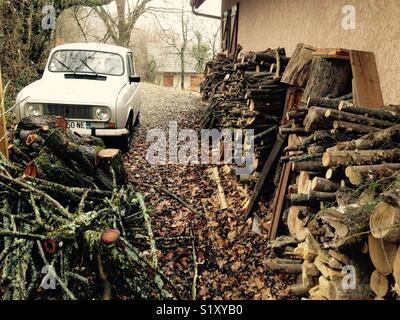 Bois de chauffage à partir de la mémoire et couper les arbres abattus, empilées et prêt pour la gravure à l'extérieur d'une maison à la campagne française. La France. Renault 4L voiture est garée Banque D'Images