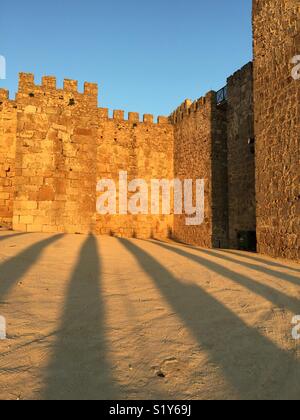 Castillo de Trujillo, Espagne, mur de l'ancien fort au coucher du soleil. Les ombres des arbres en premier plan visible. Banque D'Images