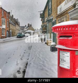 Paysage urbain d'hiver et un post rouge fort avec de fortes chutes de neige dans la région de West Drayton, Dorset, Angleterre durant la tempête de verglas Emma, Mars 2018 Banque D'Images