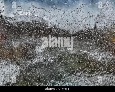 La pluie sur la fenêtre d'une maison. La pluie verglaçante est précipitations qui tombent comme des gouttelettes d'eau surfondues jusqu'à ce qu'il frappe une surface froide lorsqu'il gèle presque instantanément Banque D'Images