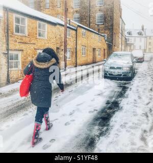 UK, météo, Sherborne, Dorset. Femme marche dans la rue bon marché dans la neige comme le soi-disant mini bête de l'Est apporte un autre souffle glacial au sud-ouest. Banque D'Images
