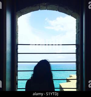 À la fille par la fenêtre par la mer Banque D'Images