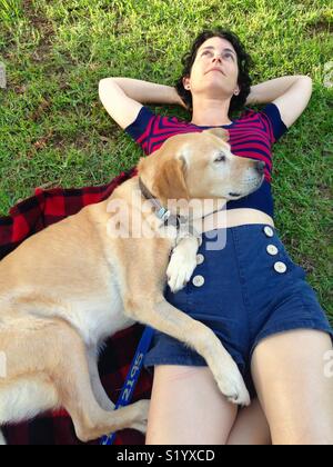 Femme et son labrador retriever couché sur son tapis sur un pique-nique dans un parc Banque D'Images