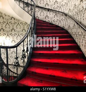 Un escalier en colimaçon avec fantaisie rouge garde-corps noir Banque D'Images