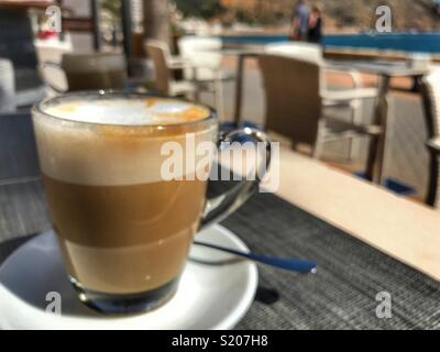 Cafe con leche, café blanc laiteux, sur une table dans un café sur la promenade au bord de l'eau dans le port de Javea / Xabia sur la Costa Blanca, Alicante Province, Comunidad Valenciana, Espagne Banque D'Images