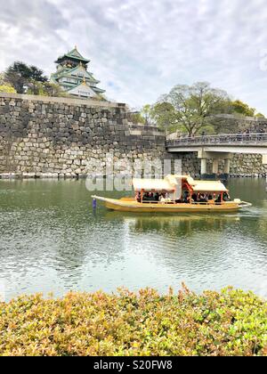Les touristes de prendre un tour de bateau sur le fossé entourant le château d'Osaka au Japon. Banque D'Images
