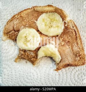 Morceau de pain partiellement mangés avec du beurre d'arachides et des tranches de banane Banque D'Images