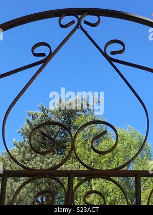 Sur la porte en fer forgé coeur journée ensoleillée avec des arbres Banque D'Images