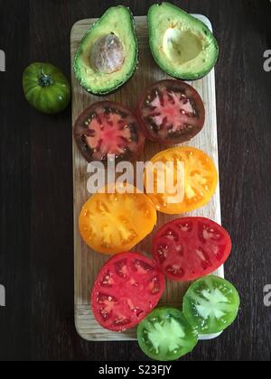 Les tomates et d'avocat on cutting board Banque D'Images