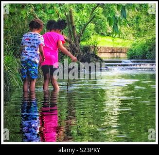 Deux enfants pagayer dans un ruisseau. Banque D'Images