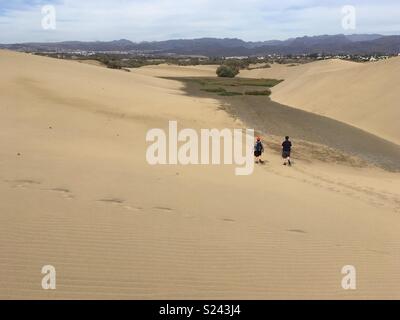 Deux personnes marchant à travers les dunes de sable, dunes de Maspalomas, Gran Canaria, Îles Canaries Banque D'Images