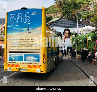 Yellow bus touristique de Funchal, Madère, à un arrêt de bus à côté d'un café à Câmara de Lobos Banque D'Images