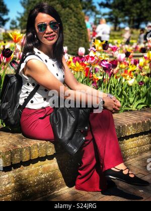 Une belle dame s'assit sur un mur dans un jardin. Banque D'Images