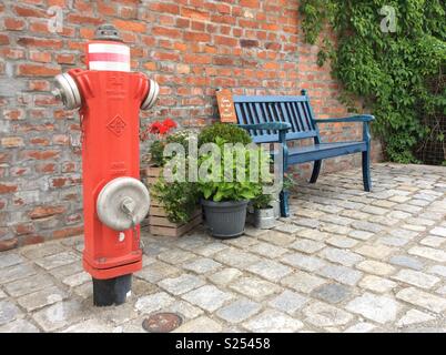 Borne-fontaine, fleurs et banc en bois en face de vintage brick wall, Bavaria, Germany, Europe Banque D'Images