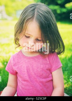 Portrait de Candide 2 ans tout-petit enfant assis dehors sur une journée ensoleillée Banque D'Images