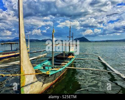 Outrigger traditionnel bateau sur le lac Taal, Philippines, avec le volcan Taal en arrière-plan. Banque D'Images