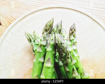 Asperges vertes sur une plaque de bois sur une table en bois Banque D'Images