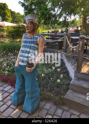 Statue en bois sculpté d'un marin accueille les clients comme ils prendre place sur la terrasse d'un café du parc à Hambourg, Allemagne. Banque D'Images