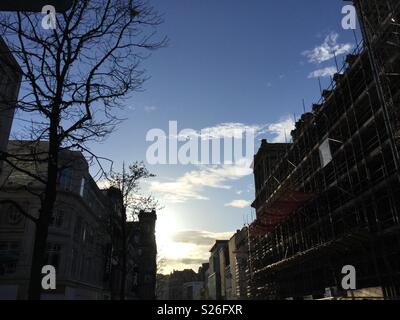 Le centre-ville de Liverpool One. Soleil se reflète sur les échafaudages. silhouette d'arbres, ciel bleu, les nuages blancs Banque D'Images