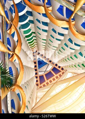 Vue depuis l'intérieur de la Burj Al Arab, Dubaï. Les balcons colorés au plafond et fournir un résumé contexte,avec le soleil en streaming l'atrium. Banque D'Images