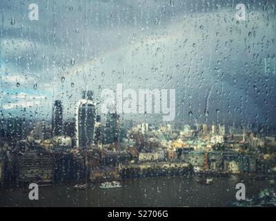 La pluie sur la fenêtre de l'Écharde de Londres, au Royaume-Uni, à la recherche de l'autre côté de la Tamise vers Fenchurch Street et sur la ville. Un arc-en-ciel s'allume le ciel que le soleil perce, illuminant la ville ci-dessous. Banque D'Images