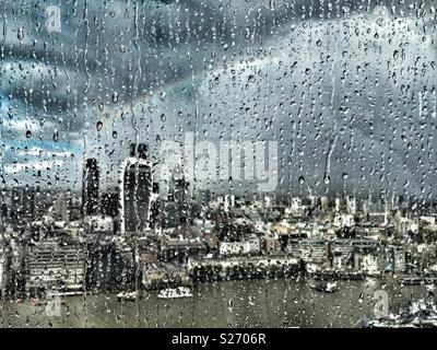 La pluie sur la fenêtre de l'Écharde de Londres, au Royaume-Uni, à la recherche de l'autre côté de la Tamise vers Fenchurch Street et sur la ville. Un arc-en-ciel s'allume le ciel que le soleil perce, illuminant la ville ci-dessous. Banque D'Images