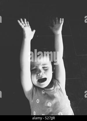 B&W image de bébé fille d'avoir une crise de colère sur un marbre Banque D'Images