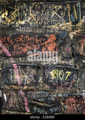 Un mur de brique avec une craie noire mots griffonnés partout il Banque D'Images