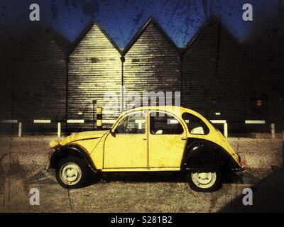 Old black' n2 CV Citroen jaune sur un fond de ciel bleu et de huttes de bois Banque D'Images