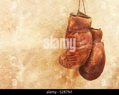 Ancienne paire de gants de boxe usé accroché sur un mur texturé Banque D'Images