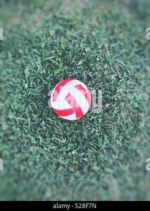 Ballon de soccer rouge et blanc sur l'herbe Banque D'Images