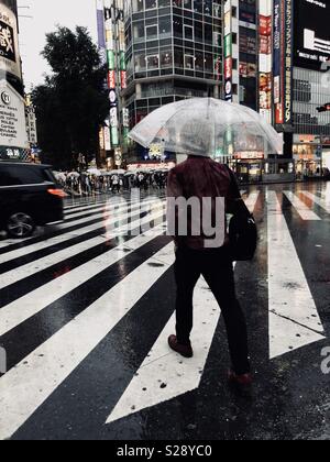 Personne avec parapluie traverse intersection dans Shinjuku, Tokyo. Juin 2018. Banque D'Images