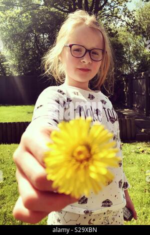 Jeune fille de 8 ans tenant une fleur jaune jonquille dans jardin Banque D'Images