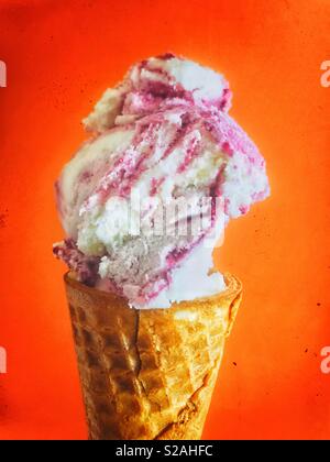 Libre de glace à la framboise dans un cornet gaufré sur fond rouge orange vif Banque D'Images
