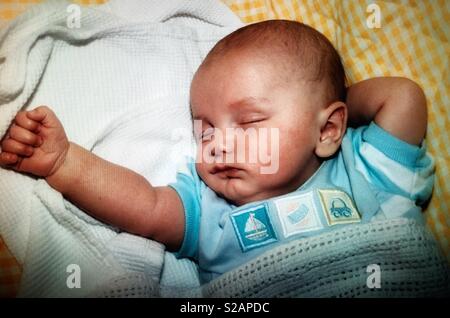 Un petit garçon dormir avec son bras étendu Banque D'Images
